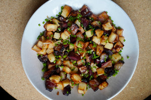 Plated dish of diced Wagyu bacon ends, diced potatoes, onions, and other vegetables on a beige surface